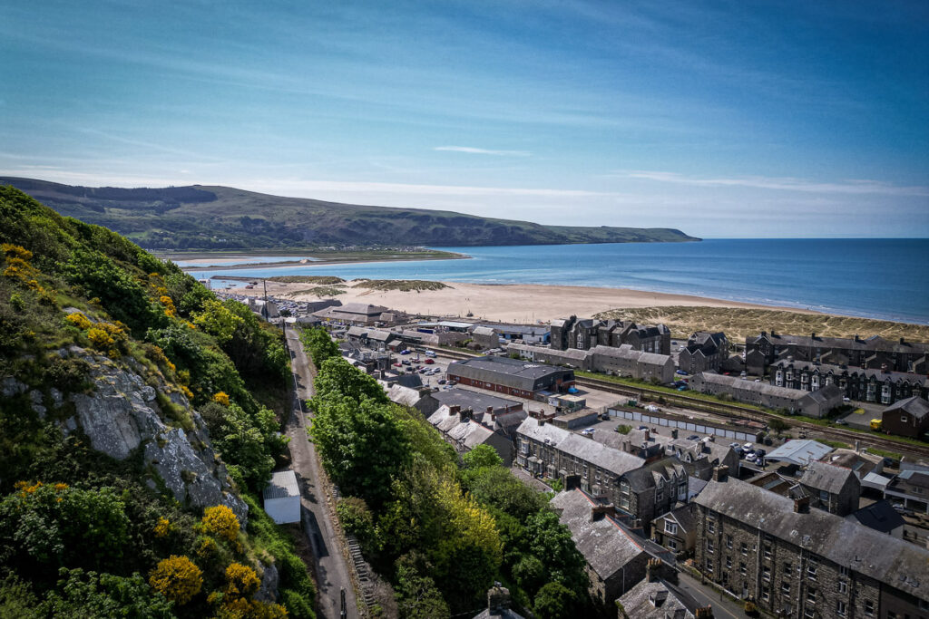 View across Barmouth rooftops towards the beach, sea and coastal hills