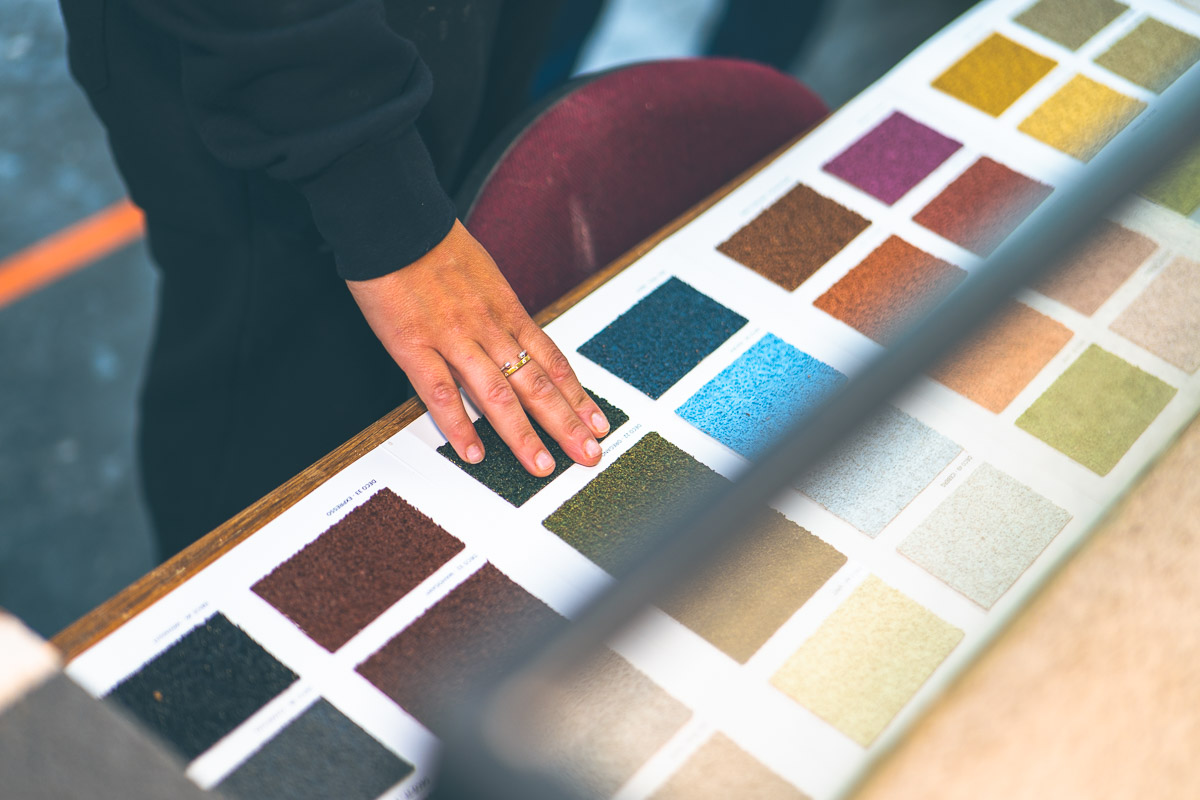A hand exploring textured cork coating colour samples on a display board