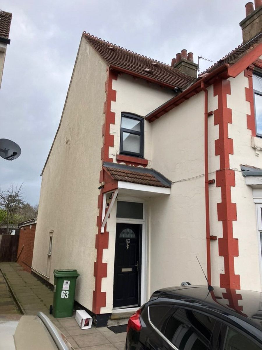 Traditional house before renovation, with weathered cream walls and red detailing