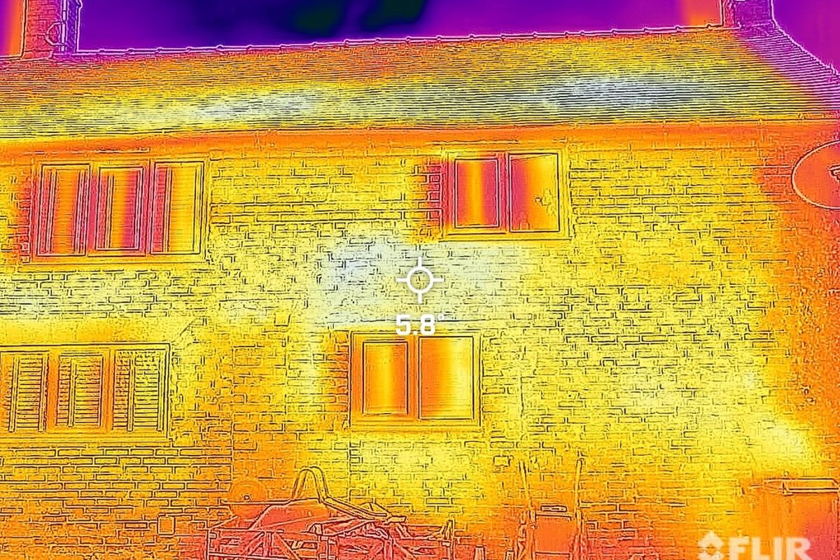 Thermal image of a brick house exterior showing temperature variation across walls, windows and roof