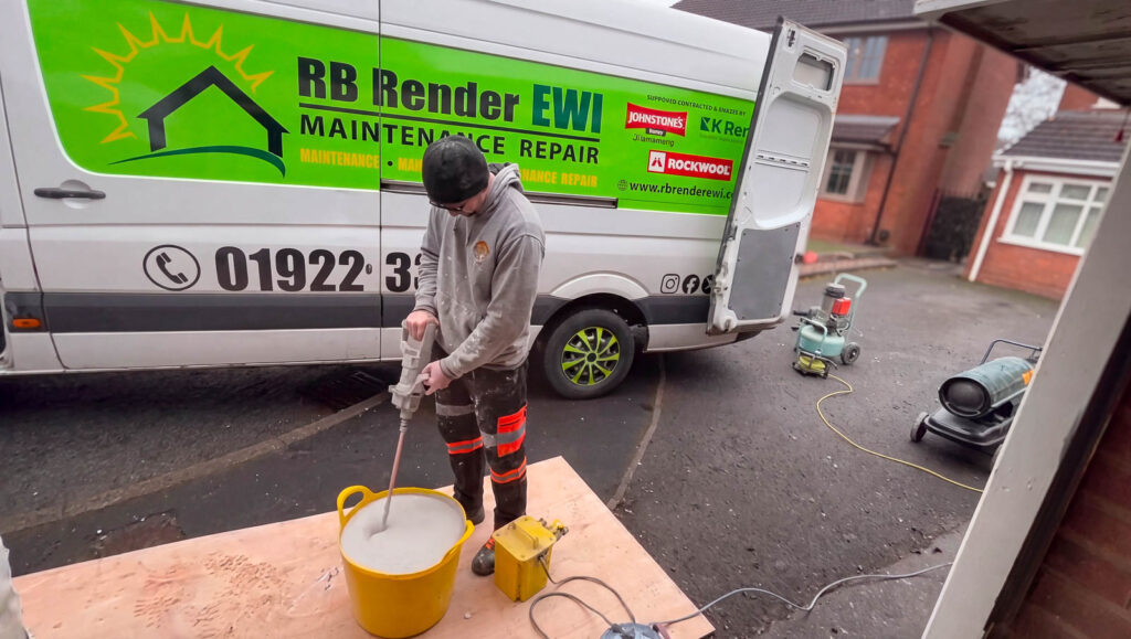 Installer mixing material in a bucket beside a trade van