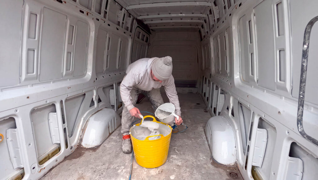 Installer preparing a spray gun inside an unlined van