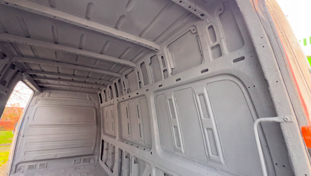 Spray-cork coating across the roof, ribs and side panels of a van interior