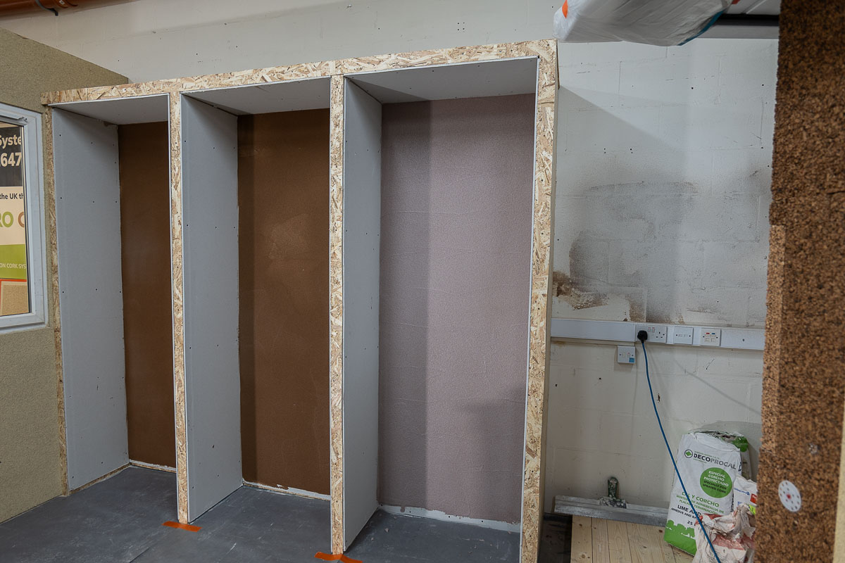 Three ECOPROCORK Academy wall bays showing successive cork and plaster stages