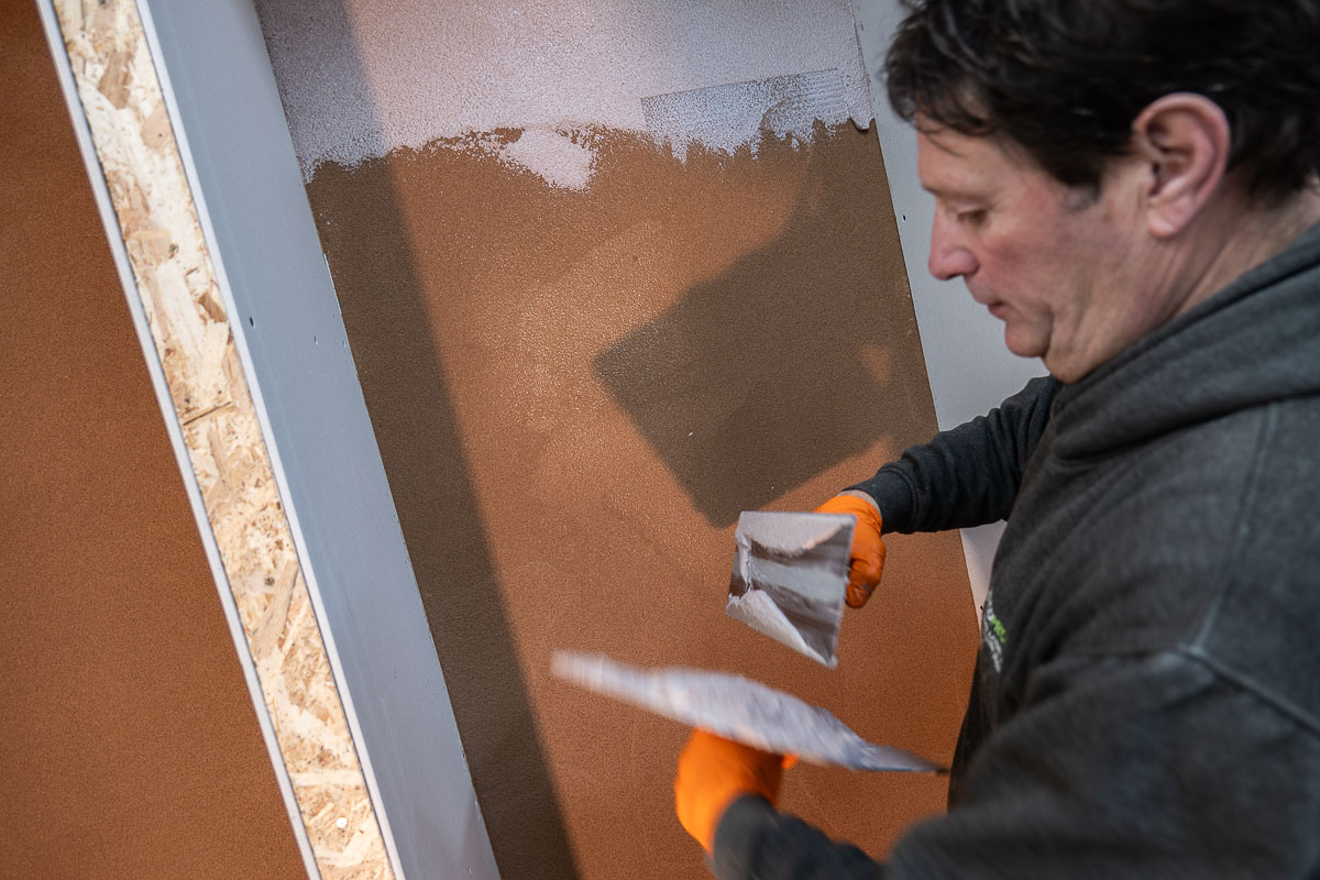 Applicator trowelling cork onto an Academy demonstration wall