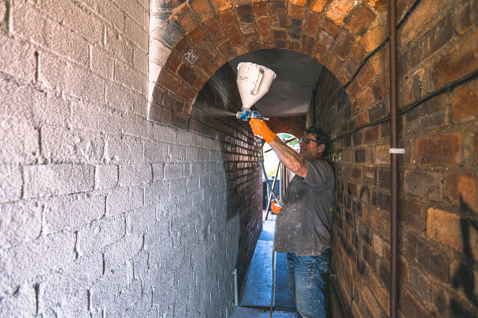 Applicator spraying cork inside the narrow arched brick passage