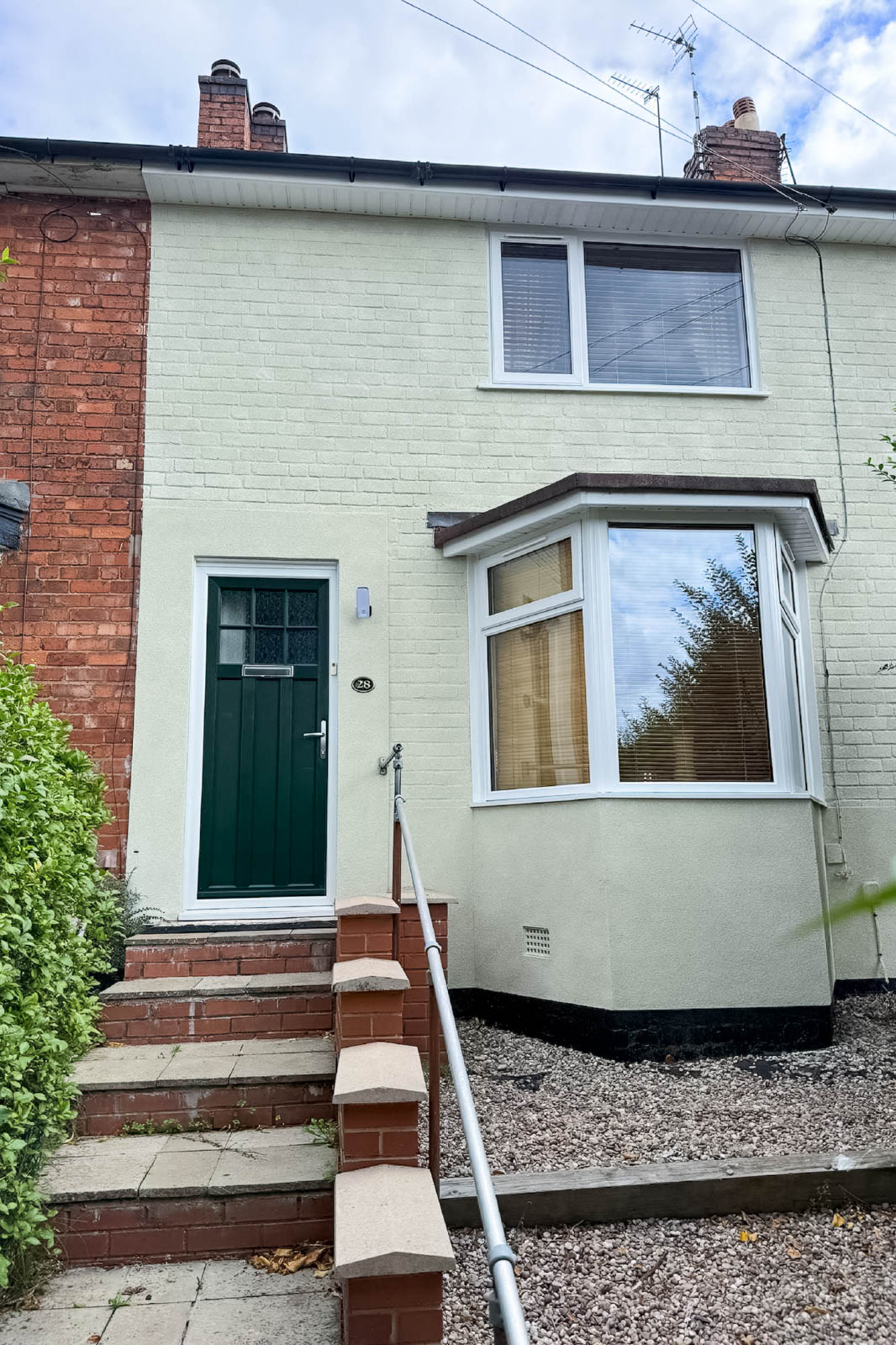 Completed Kings Norton home with light cork-coated brick frontage, bay window and green entrance door