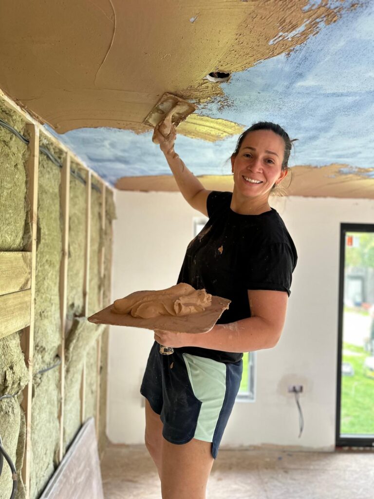 She Plasters applicator plastering an interior ceiling